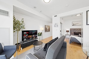 Una sala de estar moderna con un televisor de pantalla plana, sofás grises, una mesa de centro y una planta.