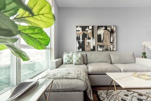 Ein modernes Wohnzimmer mit einem grauen Sofa, einem Couchtisch und abstrakter Kunst an der Wand.