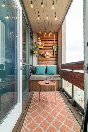A balcony with a wooden bench, a small table, and hanging plants. - Luxe Downtown 1BR Suite, Workspace & 55" TV (Toronto)