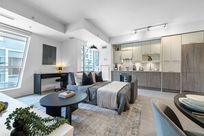 Eine moderne Wohnung mit Wohnbereich, Esstisch, Küche und einem großen Fenster für natürliches Licht.
