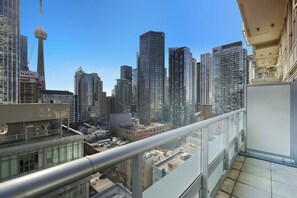 A high-rise building with a glass balcony overlooking a cityscape. - Stylish TO Condo CN Tower View Walk Score 99 | Parking Available (Toronto)