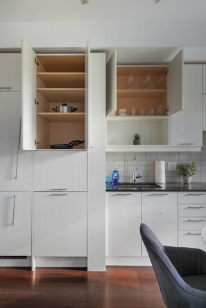 A modern kitchen with white cabinetry, open shelves, and a countertop with a sink and dish soap. - Stylish TO Condo CN Tower View Walk Score 99 | Parking Available (Toronto)