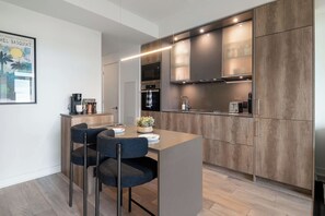 A modern kitchen with wooden cabinets, a built-in oven, and a coffee machine. - Luxury Yorkville 1BR Suite with Private Balcony | Parking Available (Toronto)