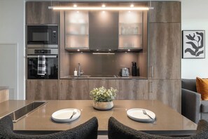 A modern kitchen with built-in appliances, a central island with seating, and a minimalist design. - Luxury Yorkville 1BR Suite with Private Balcony | Parking Available (Toronto)