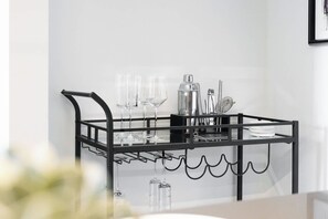 Een zwarte metalen barwagen met wijnglazen en een koffiekan.