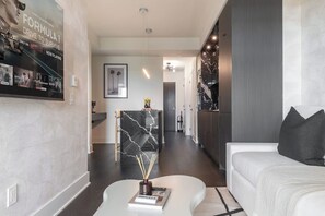 Una sala de estar moderna con un sofá blanco, una mesa de centro de mármol y una pared decorativa de mármol blanco y negro.