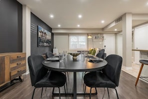 Un espace repas moderne avec une table ronde, des chaises noires et un buffet en bois.
