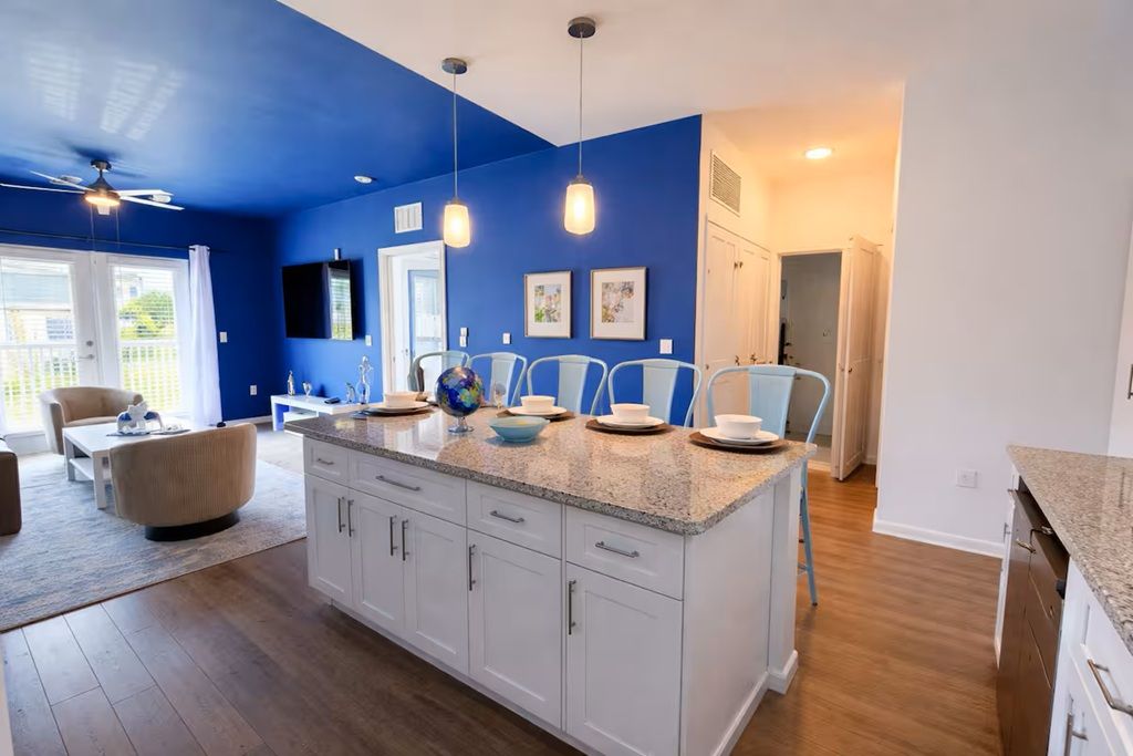 A modern kitchen with white cabinets, a granite countertop, and pendant lighting.