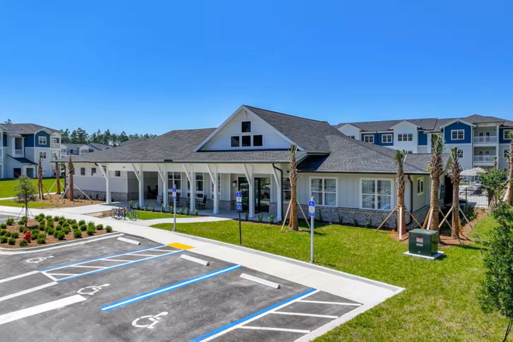 A building with a covered entrance, a parking lot with marked handicapped spaces, and a clear blue sky.