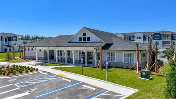 A building with a covered entrance, a parking lot with marked handicapped spaces, and a clear blue sky.