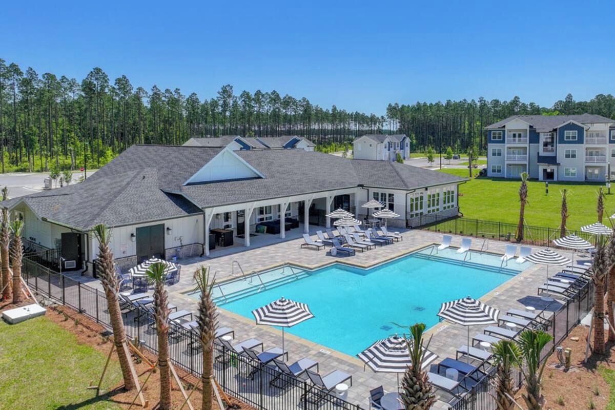 A hotel with a swimming pool, outdoor lounge chairs, and a covered patio area.