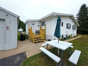 A small, single-story house with a porch, a wooden staircase, and a picnic table with benches. - Starlight Retreat located near Pictured Rocks and access to ATV/Snowmobile Trail (Shingleton)