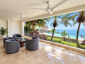 Ein modernes Wohnzimmer mit Balkon mit Blick auf Strand und Meer.