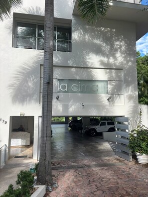 A modern building with a large glass facade, a reception area, and a parking garage with vehicles. - The Perfect Sunset at Cima 3 Vallarta: Ocean View and Pool (Puerto Vallarta)