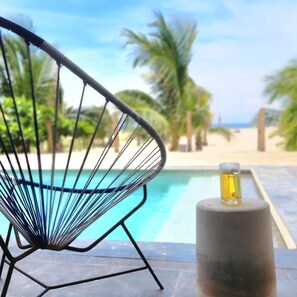 En stol ved en pool med et glas øl på et piedestal.