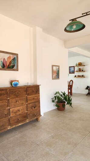Quarto com cômoda de madeira, planta em vaso e luminária pendente.