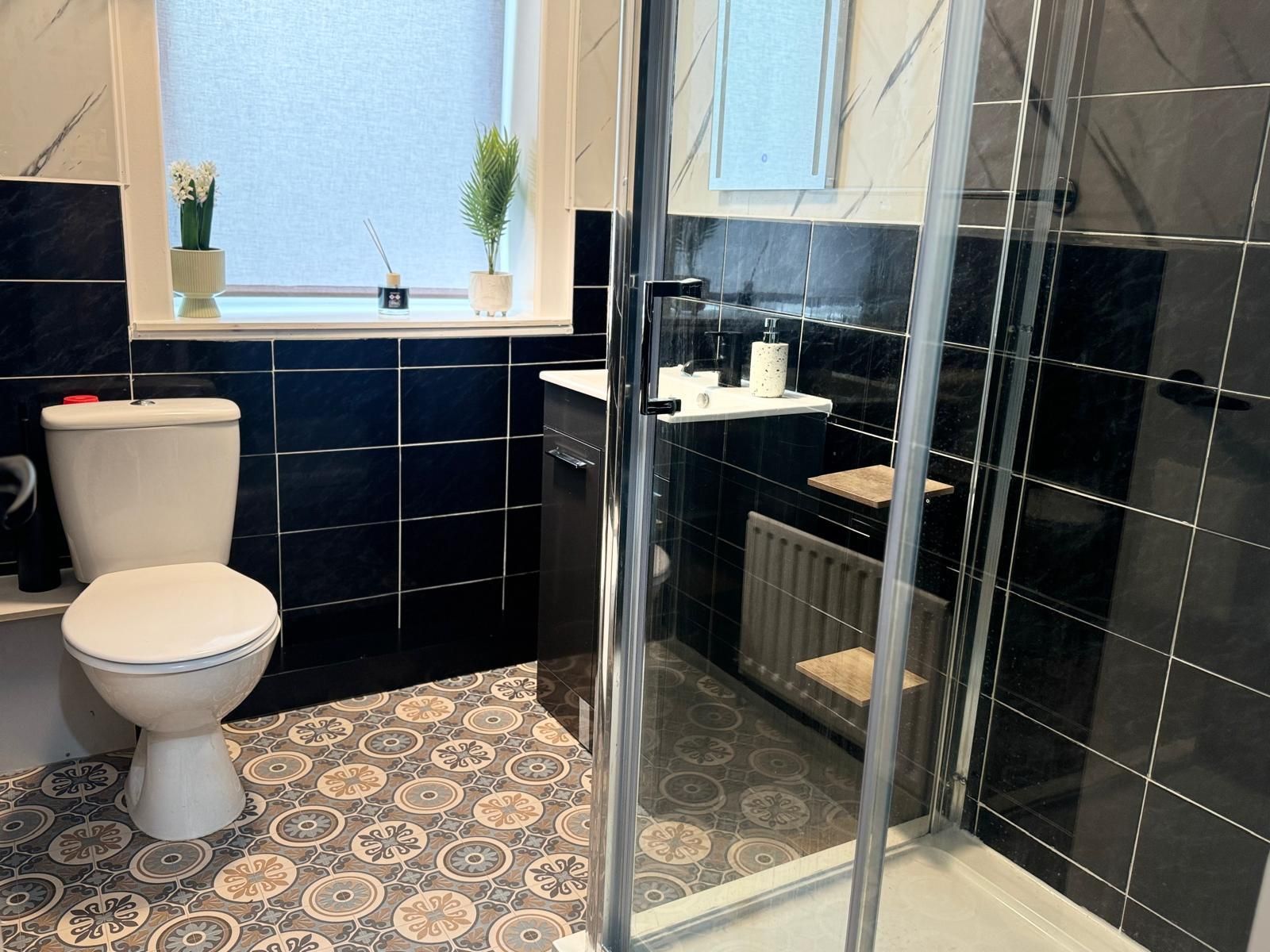 A bathroom with a toilet, a shower with a glass door, and a sink with a mirror above it.