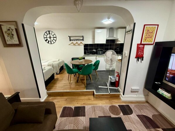 Una sala de estar moderna con un sofá, un comedor con mesa y sillas, y una cocina al fondo.