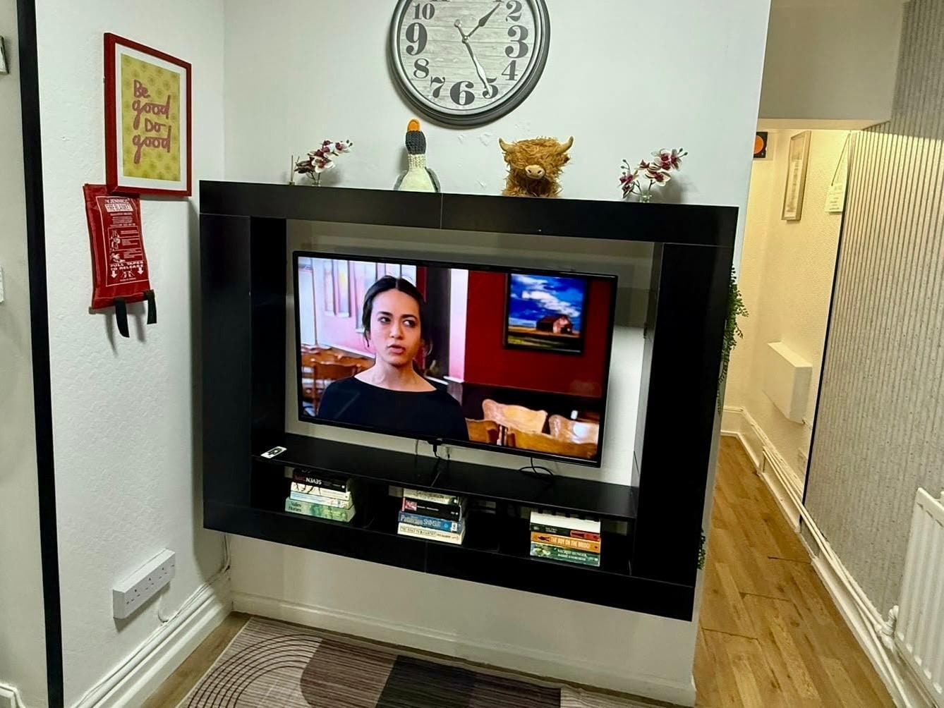 A television mounted on a wall with a clock above it.