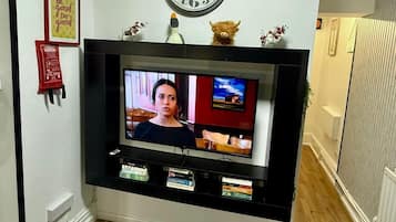 A television mounted on a wall with a clock above it.