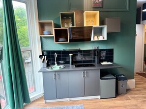 Una cocina compacta con diseño moderno, que cuenta con estufa integrada, un lavamanos y un pequeño cubo de basura.