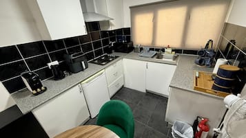 A compact kitchen with a gas stove, coffee maker, and a sink.
