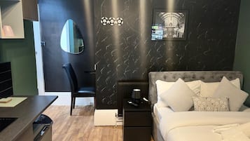 A bedroom with a bed, bedside tables, a chair, a desk, and a mirror.