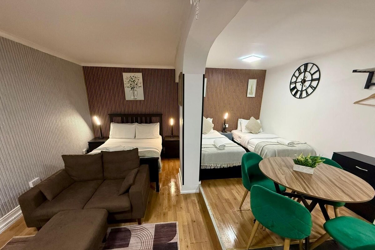 Una habitación de hotel moderna con sofá, una mesa de comedor con sillas y dos camas.