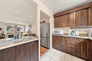 A modern kitchen with wooden cabinets, stainless steel appliances, and a granite countertop. - Spacious Toronto nest 6BR/4.5BA, Free Parking, 2 kitchens near 401 & Zoo (Toronto)