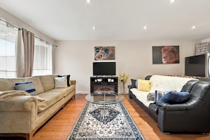 A living room with a sofa, a coffee table, a TV, and decorative items. - Spacious Toronto nest 6BR/4.5BA, Free Parking, 2 kitchens near 401 & Zoo (Toronto)