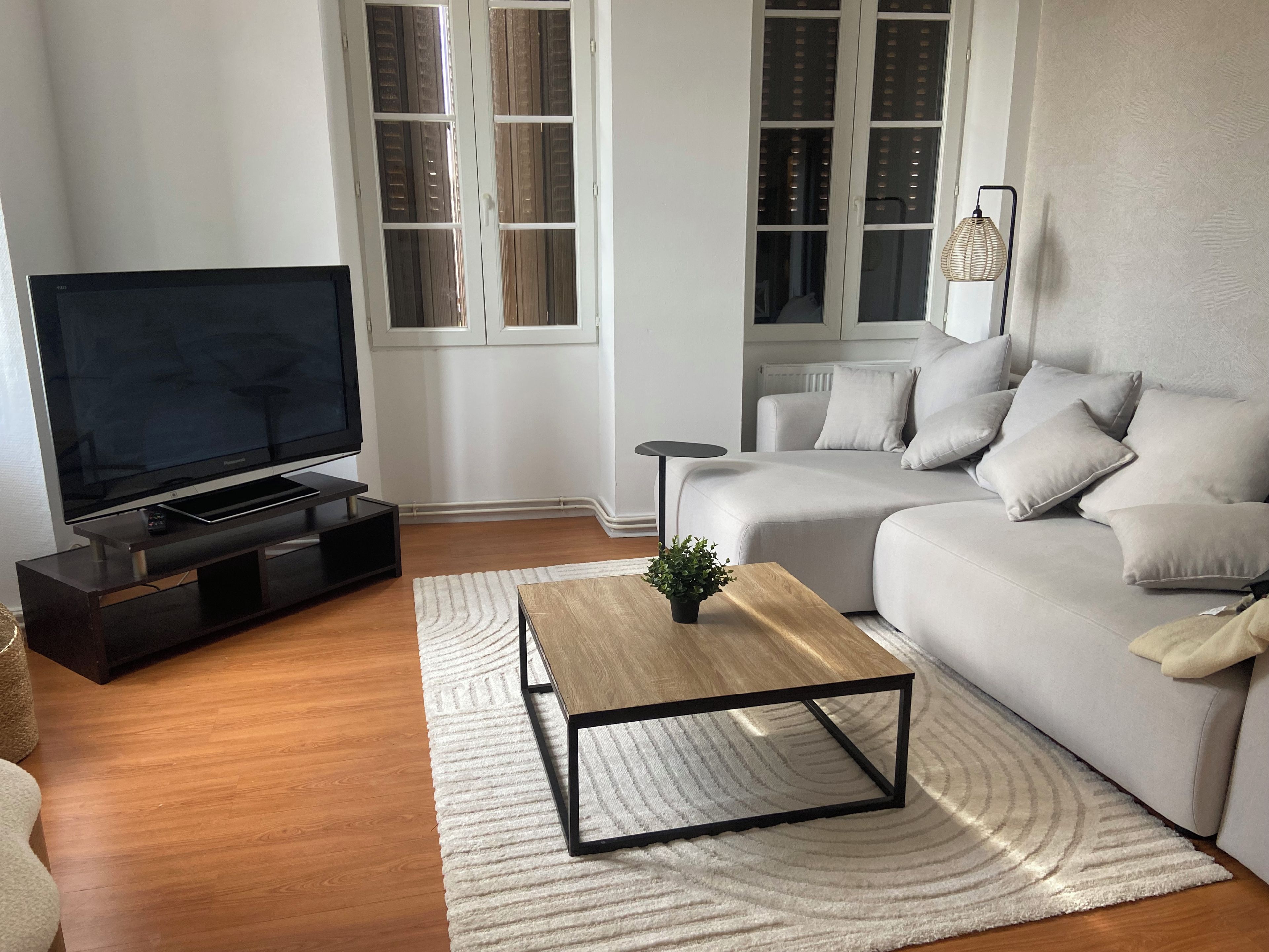 Ett modernt vardagsrum med en platt-TV, en soffa, ett soffbord och ett litet sidobord.