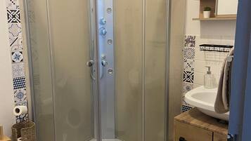 Un espace douche d’angle avec une porte en verre, un lavabo et un meuble en bois.