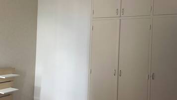 Een slaapkamer met een bed, een kledingkast en een hanglamp.