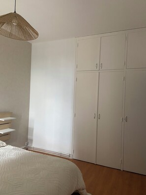 Een slaapkamer met een bed, een kledingkast en een hanglamp.
