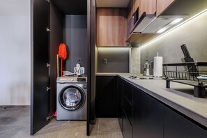 A compact kitchen with a built-in washing machine, a countertop with a knife block, and a hanging mop. - w* | Enchanting Loft w/ Balcony in Tabacalera (Ciudad de México)