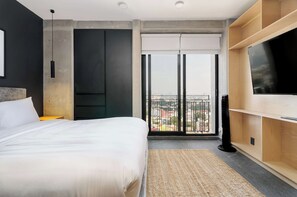 A modern hotel room with a large bed, a flat-screen TV, and a balcony with a city view. - w* | Enchanting Loft w/ Balcony in Tabacalera (Ciudad de México)