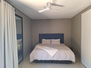 A bedroom with a bed, a ceiling fan, and a window with curtains. - Nest24: Comfortable King Size Bed Apartment Near Gold Reef City (Johannesburg South)