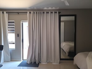 A hotel room with a bed, a large mirror, a door with curtains, and a view of the outside. - Nest24: Comfortable King Size Bed Apartment Near Gold Reef City (Johannesburg South)