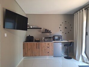 A compact kitchen with a flat-screen TV, a microwave, a toaster, and a refrigerator. - Nest24: Comfortable King Size Bed Apartment Near Gold Reef City (Johannesburg South)