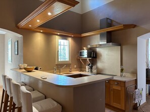 A modern kitchen with a central island, built-in microwave, and stainless steel appliances. - A Magnificent Haven of Peace (Mas-Blanc-des-Alpilles)