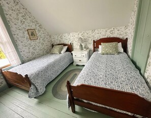 A room with two single beds, a nightstand, and a small table. - Charming Newly Renovated Downtown Winter Harbor Retreat - Minutes to Schoodic! (Winter Harbor)