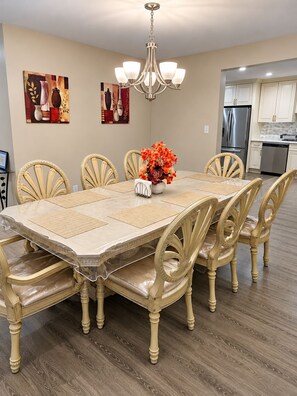 A dining room with a marble table, beige chairs, a chandelier, and artwork on the walls. - Stunning Poconos Mountain Retreat with Spacious Rooms, Pool Table and Family Fun (Tobyhanna)