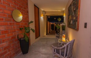 A hallway with a brick wall, a round mirror, a potted plant, wicker chairs, and a table with a lamp. - Loft with a King-size bed in San Felipe (Oaxaca de Juárez)