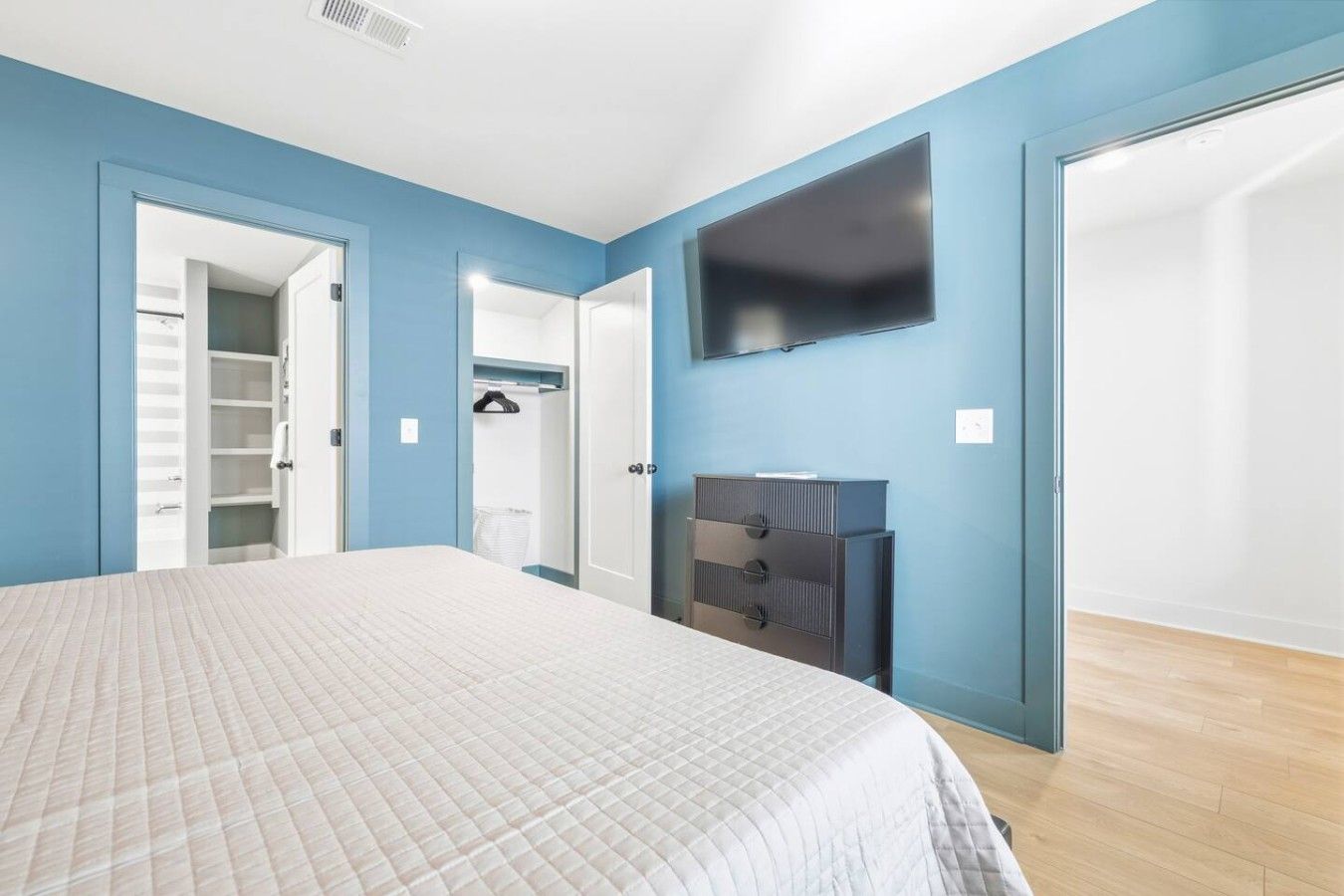 Un dormitorio con cama, armario, televisor y ropero.