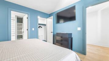 Un dormitorio con cama, armario, televisor y ropero.