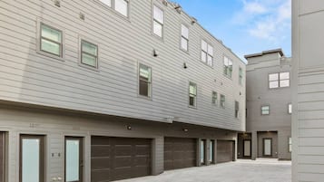 A multi-story residential building with a flat facade, multiple garage doors, and a clear sky.