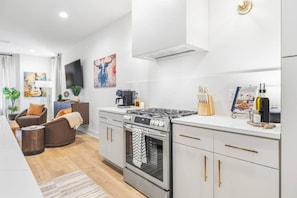 A fully equipped kitchen featuring stainless steel appliances, seating for four at the island, and all the essentials you need to cook and dine at home. - Rooftop with TV, Dining, and BBQ Grill - 3 mi Downtown + Garage (Nashville)