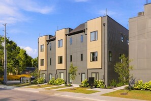 A modern multi-story residential building with a flat roof, large windows, and a symmetrical facade. - Rooftop with TV, Dining, and BBQ Grill - 3 mi Downtown + Garage (Nashville)