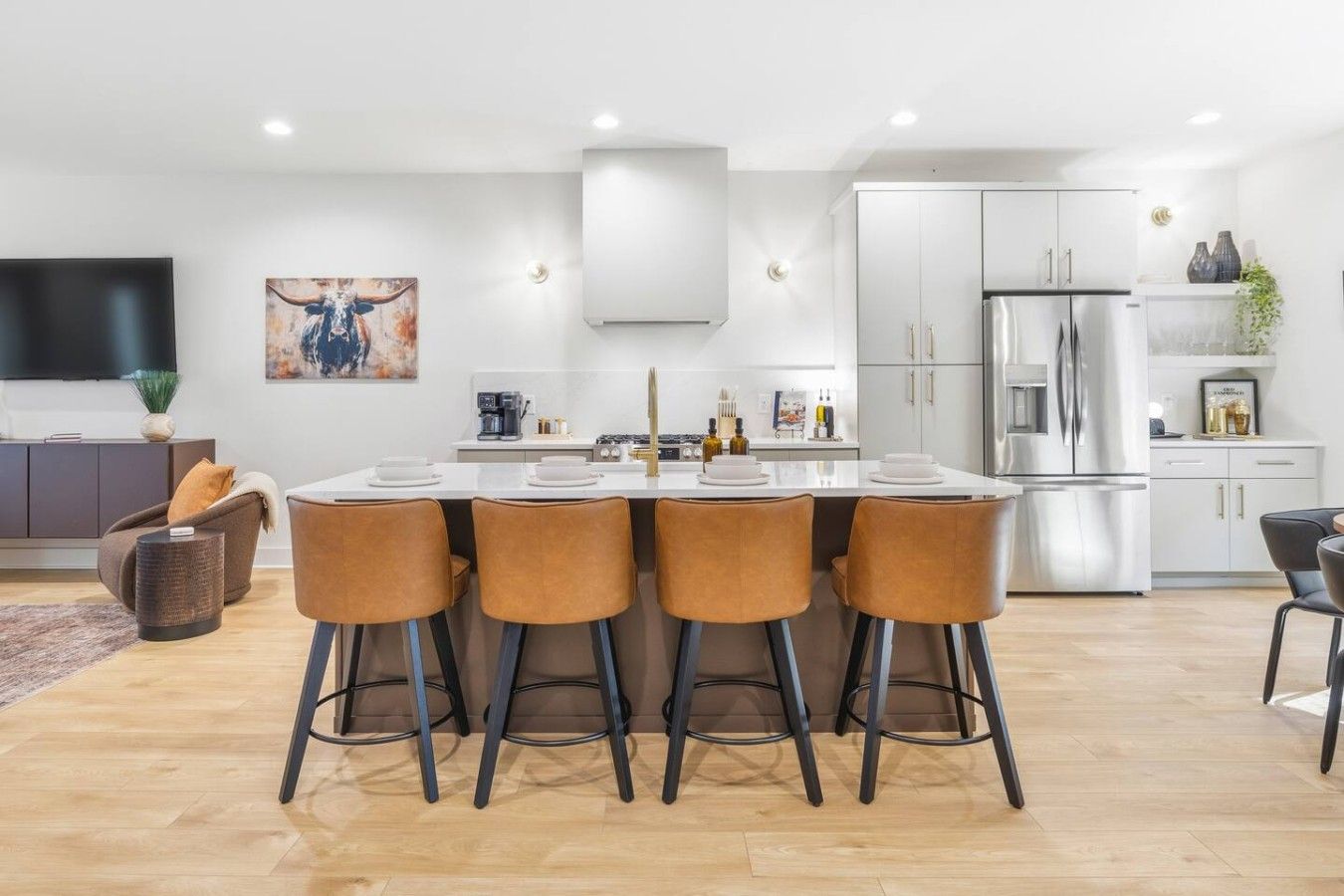 A modern kitchen with a central island, stainless steel appliances, and a dining area with four chairs.