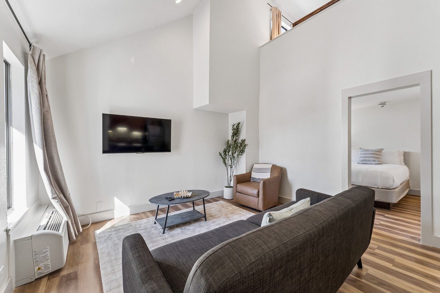 Un salon moderne avec un téléviseur à écran plat, un canapé, une table basse et un fauteuil.